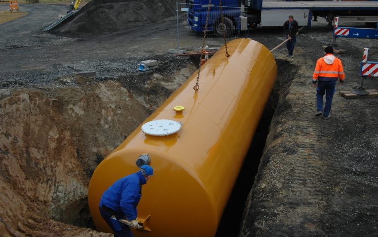 Erdtank schwebt am Kran über der Grube